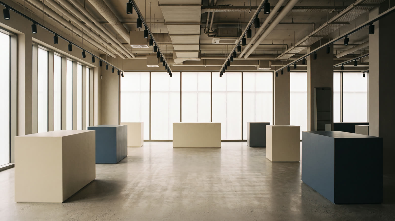Showroom commercial : plateau libre, sol béton lissé et façade vitrée — une surface d'exposition dont le classement en magasin conditionne le tarif au m².